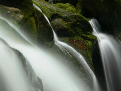 Trick
Waterfalls don't really look like this. A local photographer is confident enough in his own work to share this trick.

Rotate the polarized filter for the least glare. Close the aperture as much as possible.(I use f-11) With the shutter speed as low as possible, (shoot for a full second if possible), start experimenting until you get just the photo you are looking for. I prefer mine a little dark so I can process them using Picasa 3. The silky look is directly tied to shutter speed and a cloudy day doesn't 
